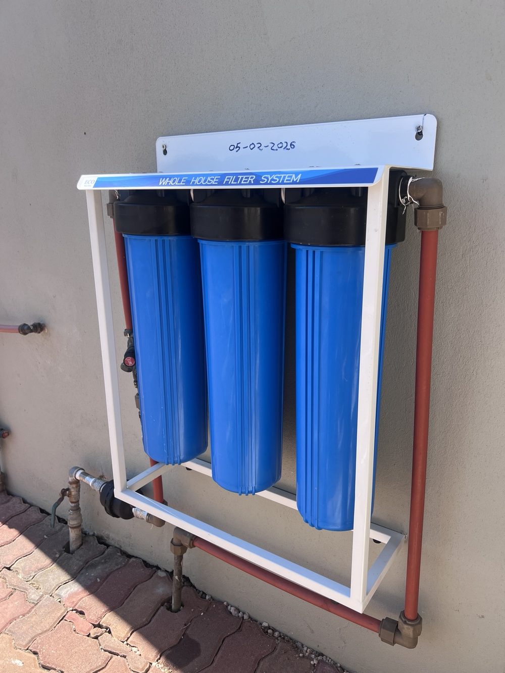 Whole house Big Blue filter system installed against an exterior wall