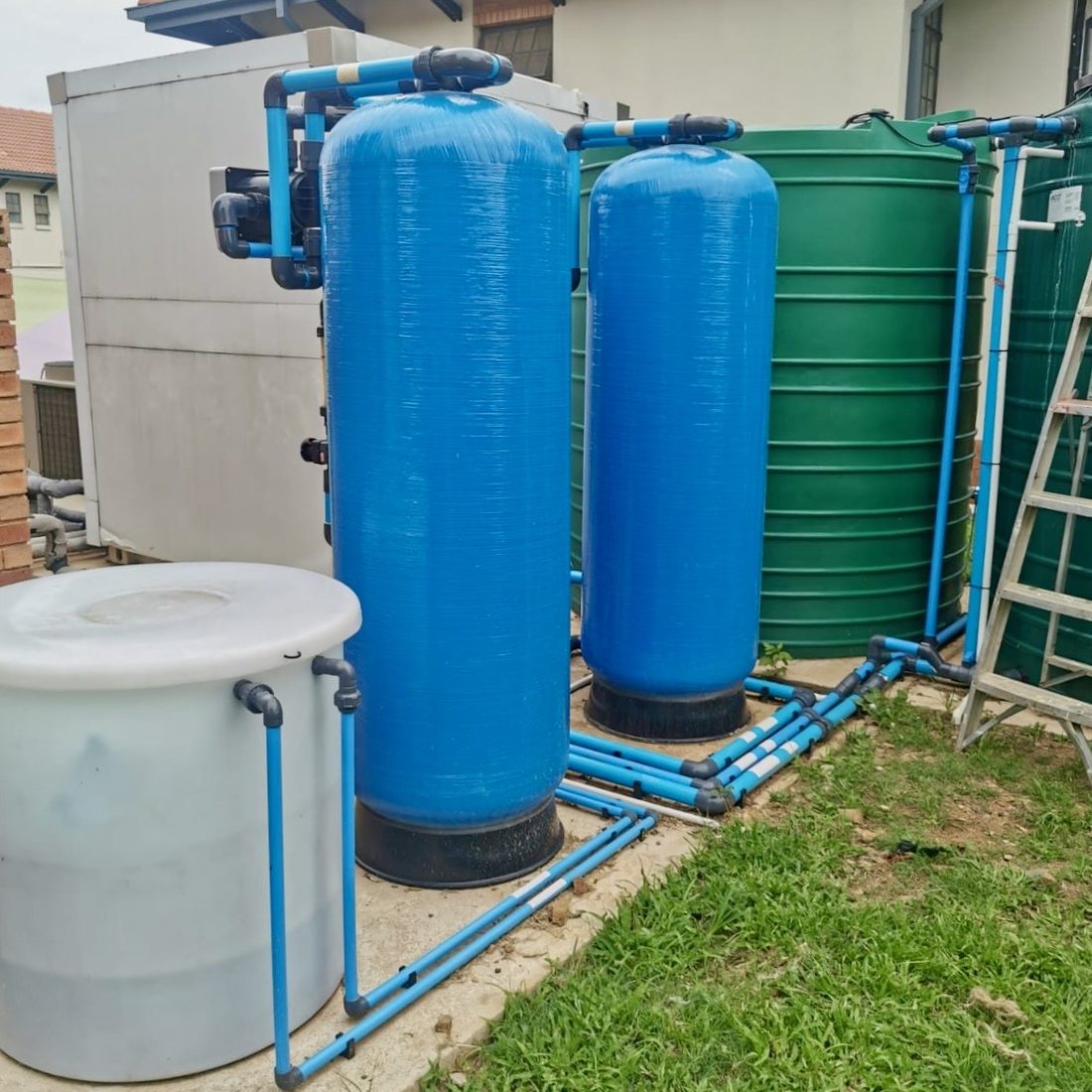 Large blue treatment vessels installed outside a property