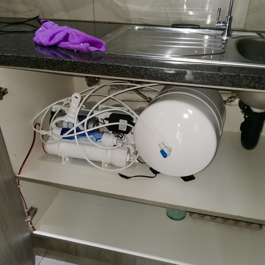 Compact under-sink reverse osmosis system inside a kitchen cabinet